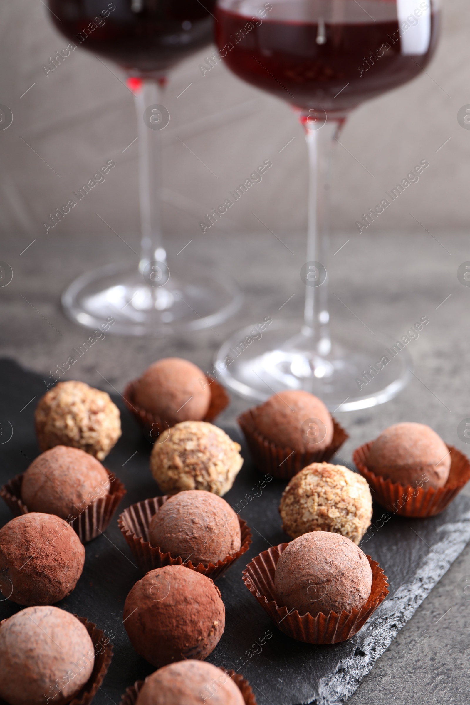 Tasty truffle bonbons and red wine on grey textured table, closeup Photo of Tasty truffle bonbons and red wine on grey textured table, closeup