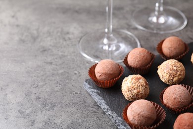 Photo of Tasty truffle bonbons on grey textured table, closeup. Space for text