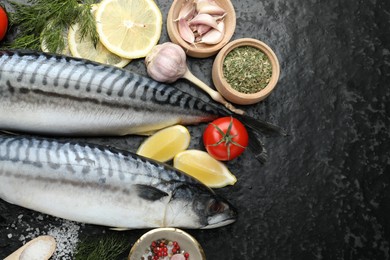 Photo of Seafood delicacies. Fresh raw mackerels and spices on black table, flat lay. Space for text