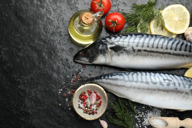 Photo of Seafood delicacies. Fresh raw mackerels and spices on black table, flat lay. Space for text