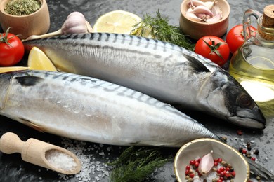Photo of Fresh raw mackerels and spices on black table, closeup. Seafood delicacies