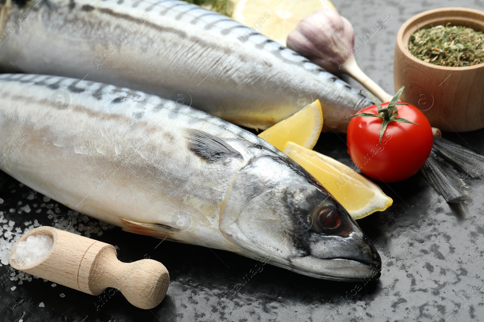 Fresh raw mackerels and spices on black table, closeup. Seafood delicacies Photo of Fresh raw mackerels and spices on black table, closeup. Seafood delicacies