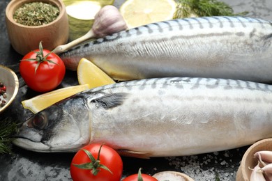 Photo of Fresh raw mackerels and spices on black table, closeup. Seafood delicacies