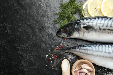 Photo of Seafood delicacies. Fresh raw mackerels and spices on black table, flat lay. Space for text