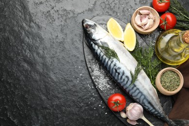 Photo of Seafood delicacies. Fresh raw mackerel and spices on black table, flat lay. Space for text