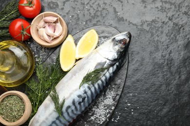 Photo of Seafood delicacies. Fresh raw mackerel and spices on black table, flat lay. Space for text