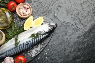 Photo of Seafood delicacies. Fresh raw mackerel and spices on black table, flat lay. Space for text
