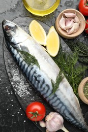 Photo of Fresh raw mackerel and spices on black table, flat lay. Seafood delicacies