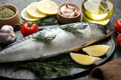 Photo of Fresh raw mackerel and spices on black table, closeup. Seafood delicacies