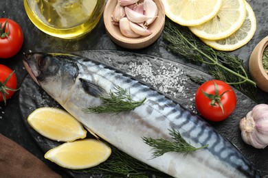 Photo of Fresh raw mackerel and spices on black table, flat lay. Seafood delicacies