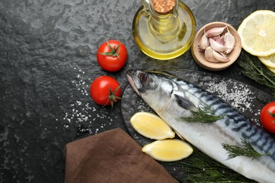 Photo of Seafood delicacies. Fresh raw mackerel and spices on black table, flat lay. Space for text