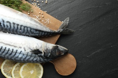 Photo of Seafood delicacies. Fresh raw mackerels and spices on black table, flat lay. Space for text