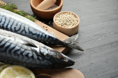 Photo of Seafood delicacies. Fresh raw mackerels and spices on black table, closeup. Space for text