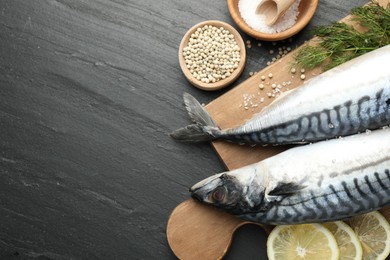 Photo of Seafood delicacies. Fresh raw mackerels and spices on black table, flat lay. Space for text