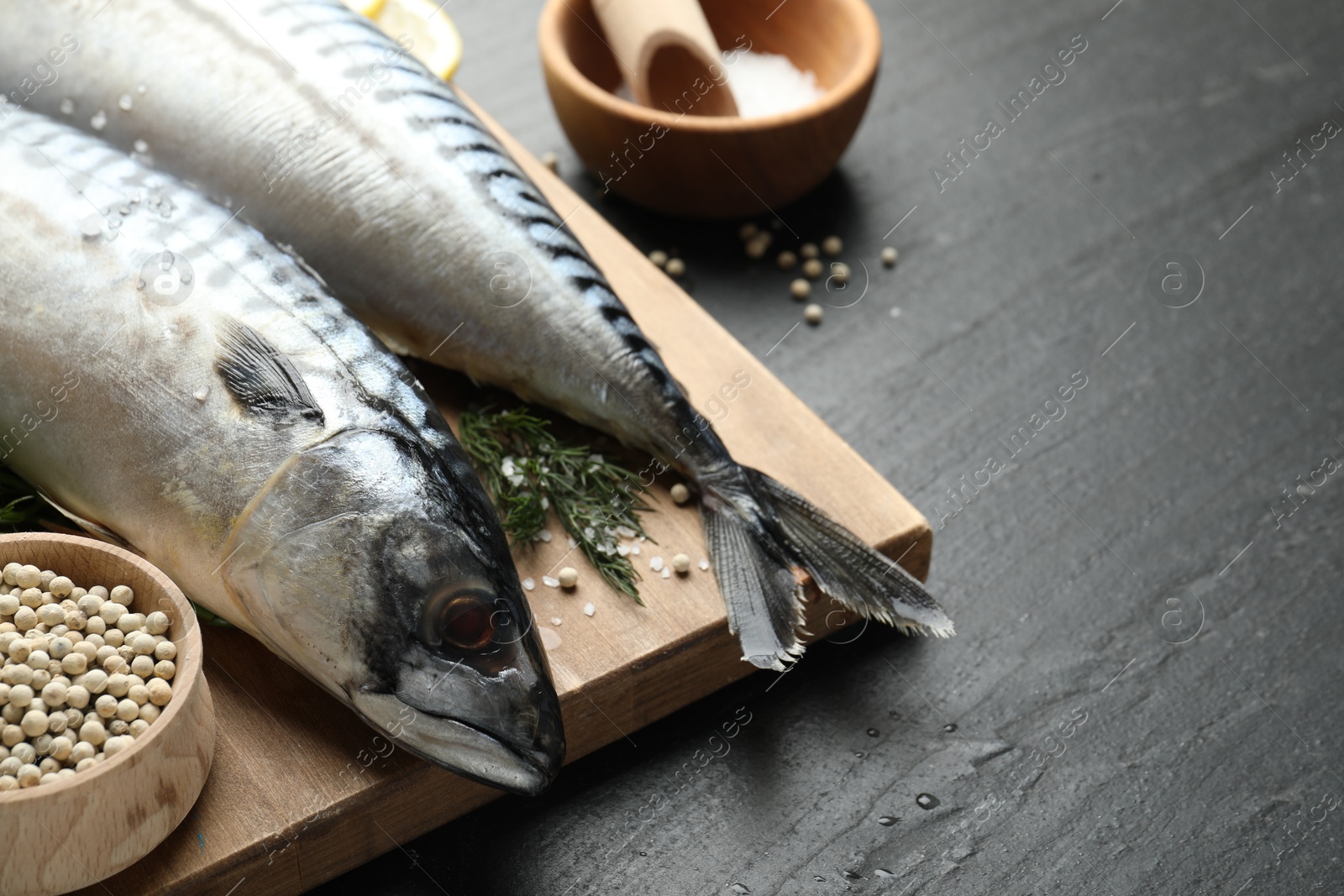 Seafood delicacies. Fresh raw mackerels and spices on black table, closeup. Space for text Photo of Seafood delicacies. Fresh raw mackerels and spices on black table, closeup. Space for text