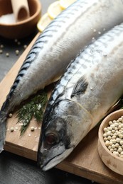 Photo of Fresh raw mackerels and spices on black table, closeup. Seafood delicacies