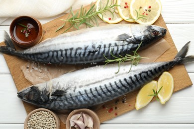 Photo of Fresh raw mackerels and spices on white wooden table, flat lay. Seafood delicacies