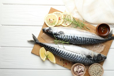 Photo of Seafood delicacies. Fresh raw mackerels and spices on white wooden table, flat lay. Space for text