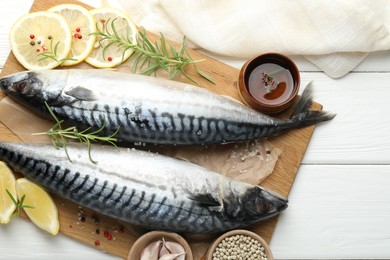 Photo of Fresh raw mackerels and spices on white wooden table, flat lay. Seafood delicacies
