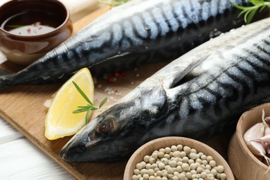 Photo of Fresh raw mackerels and spices on white wooden table, closeup. Seafood delicacies