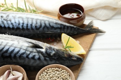 Photo of Seafood delicacies. Fresh raw mackerels and spices on white wooden table, closeup. Space for text
