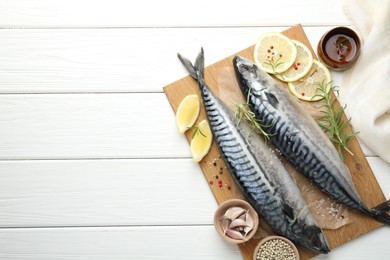 Photo of Seafood delicacies. Fresh raw mackerels and spices on white wooden table, flat lay. Space for text