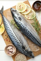 Photo of Fresh raw mackerels and spices on white wooden table, flat lay. Seafood delicacies
