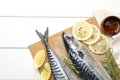 Photo of Seafood delicacies. Fresh raw mackerels and spices on white wooden table, flat lay. Space for text