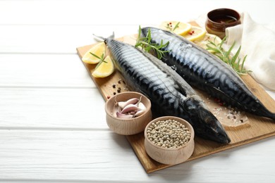 Photo of Seafood delicacies. Fresh raw mackerels and spices on white wooden table, closeup. Space for text