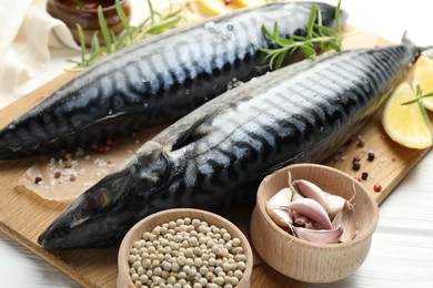 Photo of Fresh raw mackerels and spices on white wooden table, closeup. Seafood delicacies