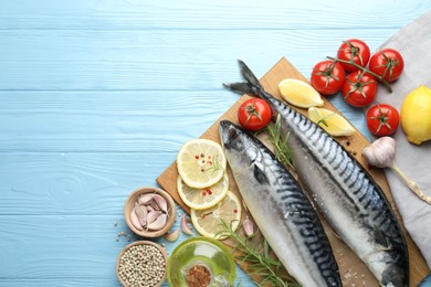 Photo of Seafood delicacies. Fresh raw mackerels and spices on light blue wooden table, flat lay. Space for text