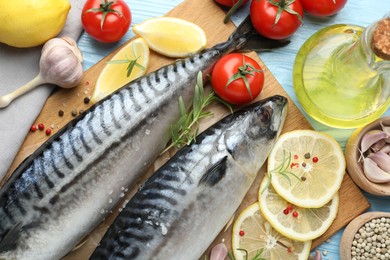 Photo of Fresh raw mackerels and spices on light blue wooden table, flat lay. Seafood delicacies