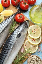 Photo of Fresh raw mackerels and spices on light blue wooden table, flat lay. Seafood delicacies