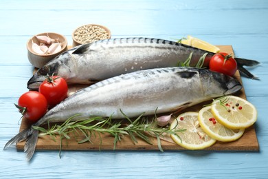 Photo of Fresh raw mackerels and spices on light blue wooden table, closeup. Seafood delicacies