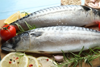 Photo of Fresh raw mackerels and spices on light blue wooden table, closeup. Seafood delicacies