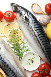 Photo of Fresh raw mackerels and spices on white table, flat lay. Seafood delicacies