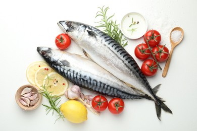 Photo of Fresh raw mackerels and spices on white table, flat lay. Seafood delicacies