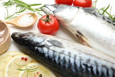 Photo of Fresh raw mackerels and spices on white table, closeup. Seafood delicacies