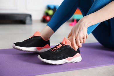 Photo of Sports injury. Young woman suffering from leg pain in fitness studio, closeup