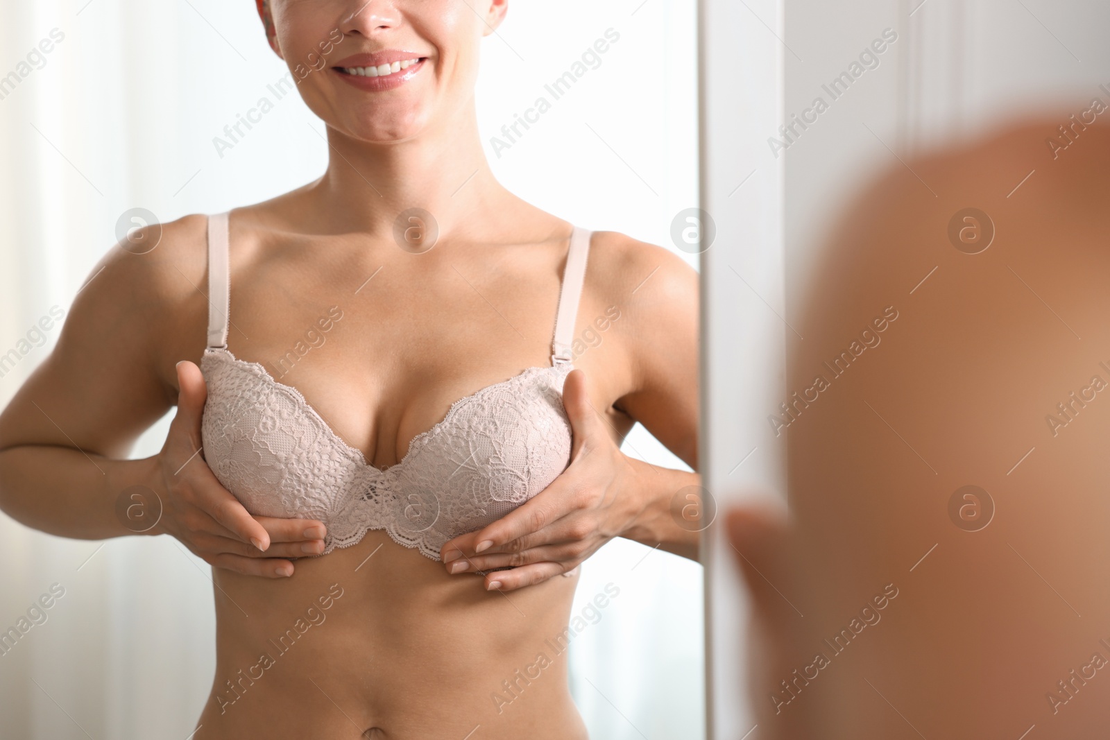 Photo of Woman wearing beautiful bra near mirror indoors, closeup
