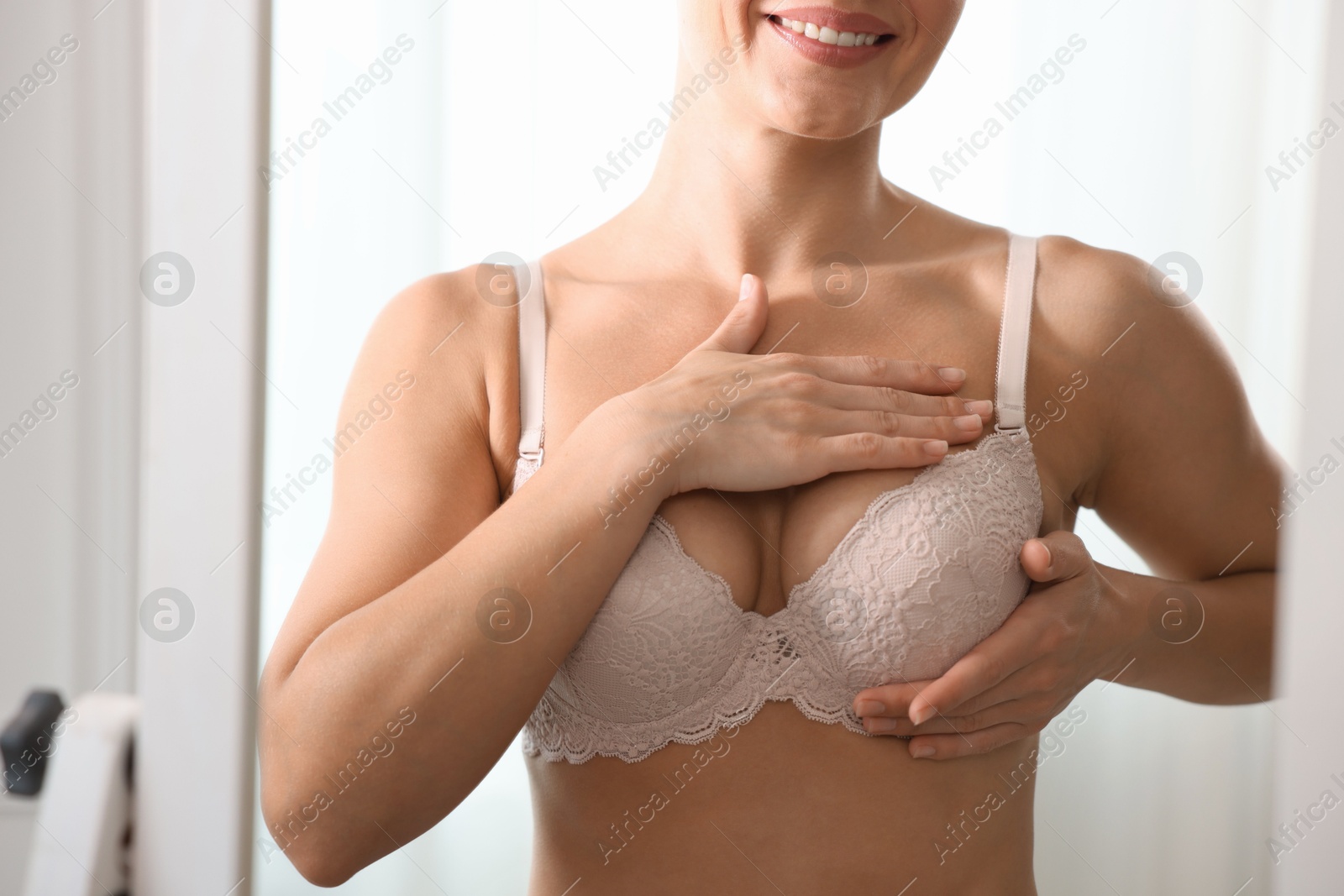 Woman wearing beautiful bra near mirror indoors, closeup Photo of Woman wearing beautiful bra near mirror indoors, closeup