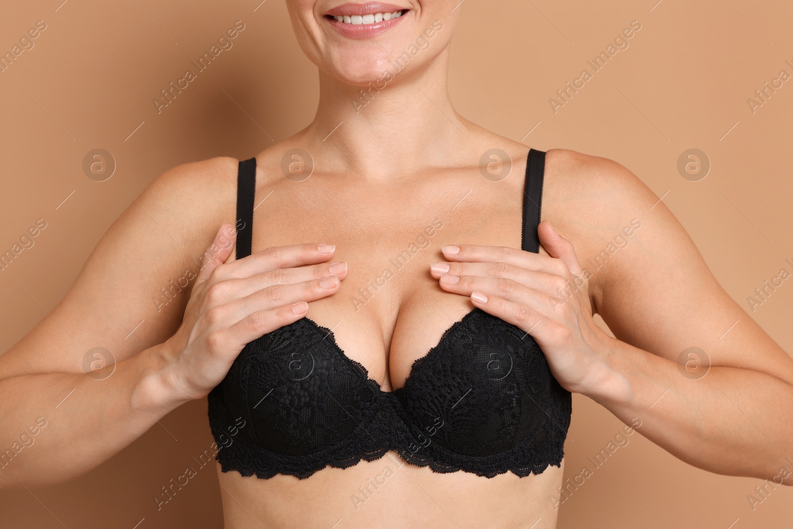 Woman wearing beautiful black bra on beige background, closeup Photo of Woman wearing beautiful black bra on beige background, closeup