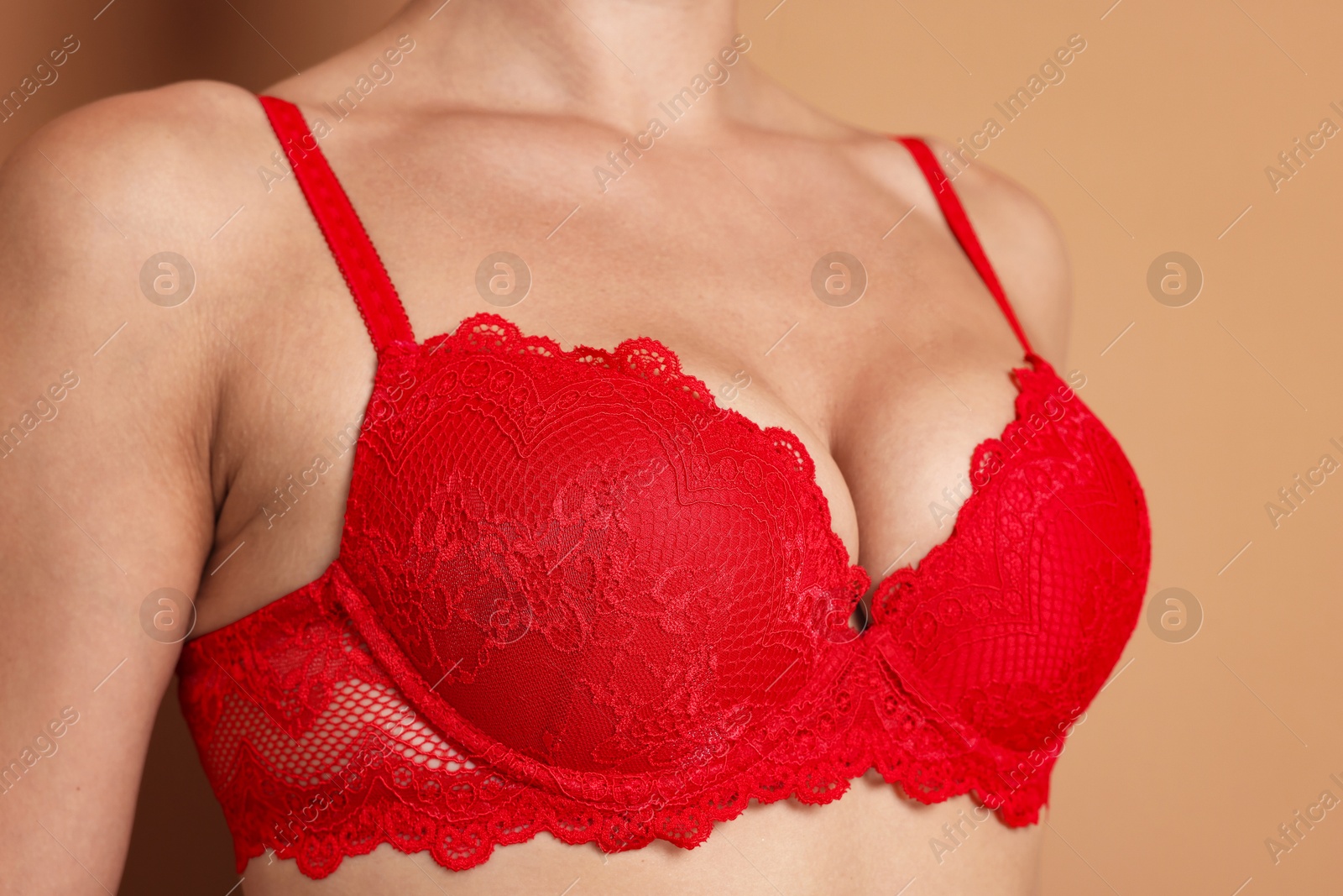 Woman wearing beautiful red bra on beige background, closeup Photo of Woman wearing beautiful red bra on beige background, closeup