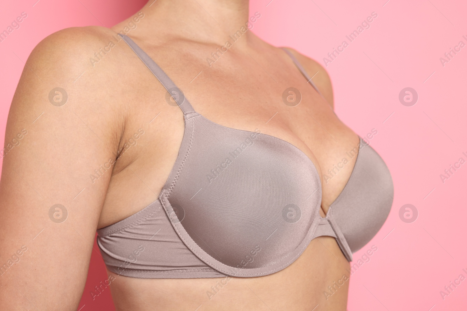 Woman wearing beautiful beige bra on pink background, closeup Photo of Woman wearing beautiful beige bra on pink background, closeup
