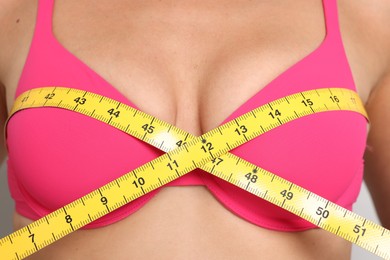 Photo of Woman in beautiful bra measuring breast circumference, closeup