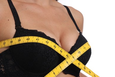 Photo of Woman in beautiful bra measuring breast circumference on white background, closeup