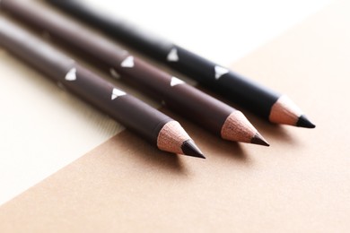 Photo of Different eyebrow pencils on beige background, closeup