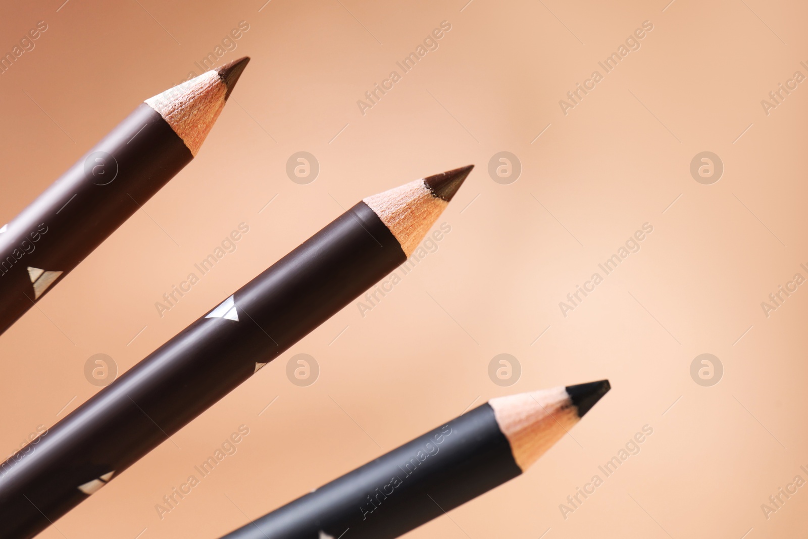 Different eyebrow pencils on beige background, closeup. Space for text Photo of Different eyebrow pencils on beige background, closeup. Space for text