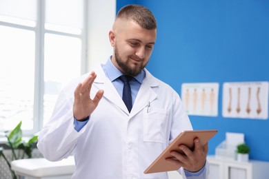 Photo of Doctor with tablet having online consultation in clinic