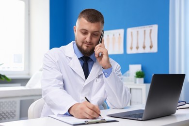 Photo of Doctor having online consultation via smartphone in clinic